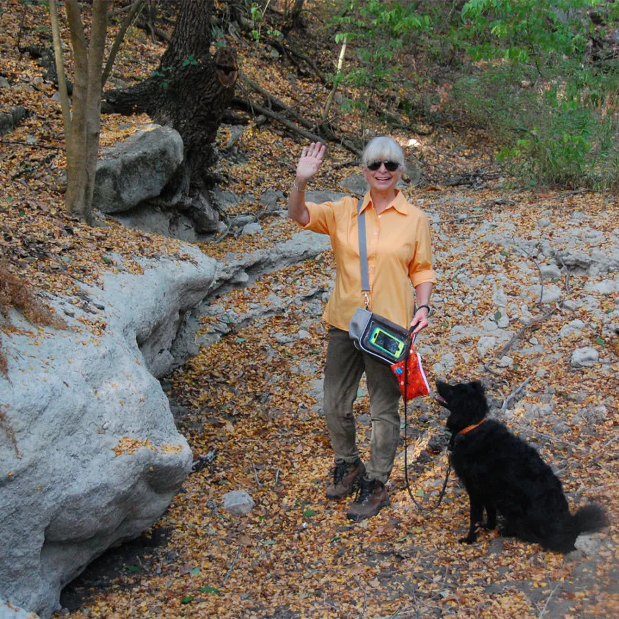 Paris Permenter, founder of DogTipper, waving at camera with black dog at side